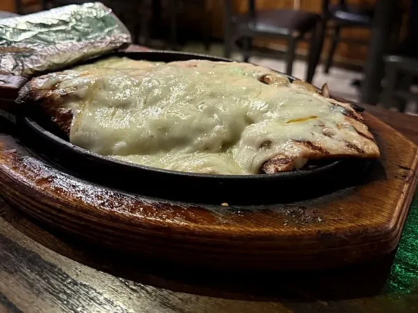 Chicken Parrilla Monterey with melted Monterey Jack cheese on a sizzling skillet at El Rancho
